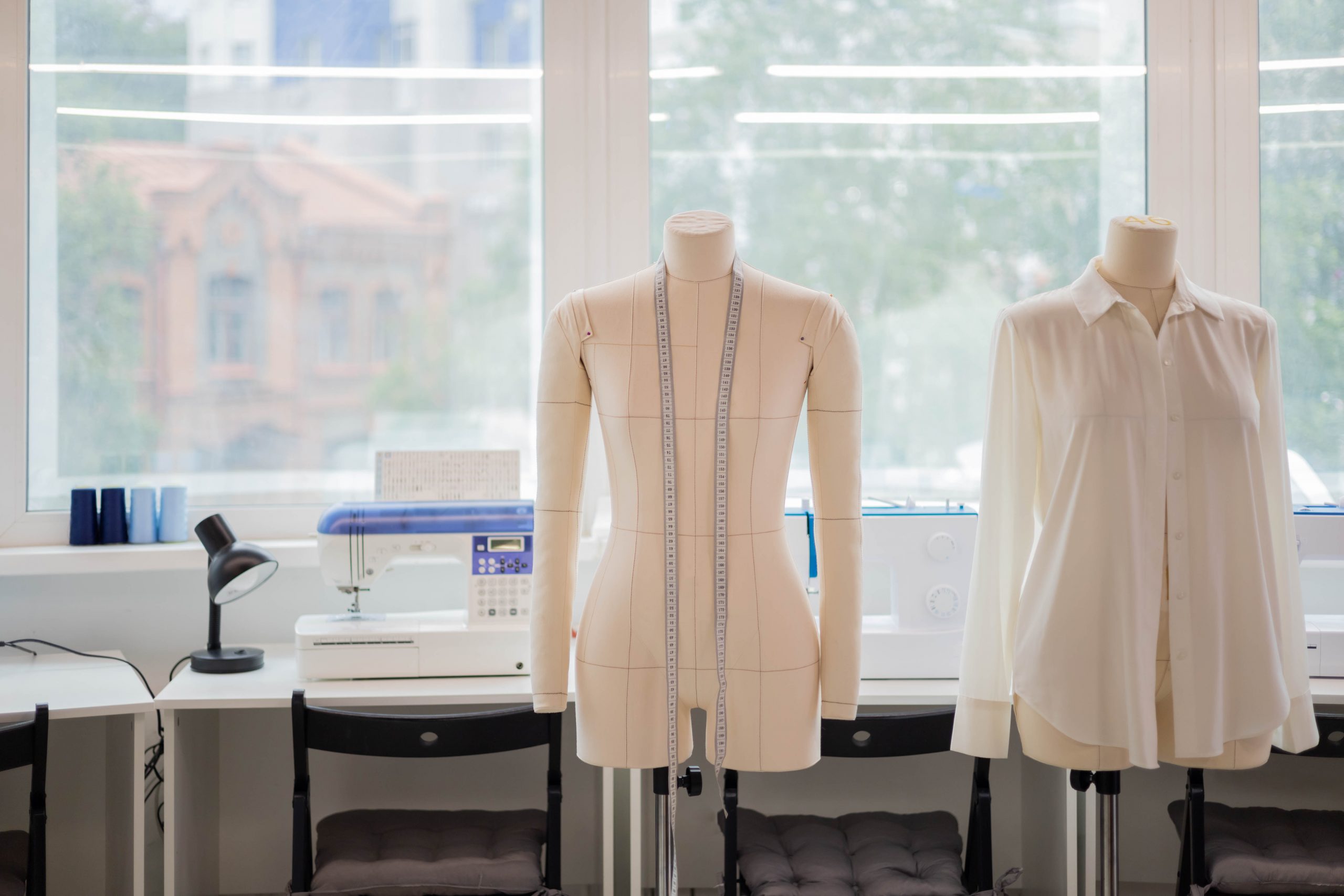 White handmade sewing shirt on dummy at studio sew workshop. Mannequin with measuring tape ready for trying clothing. Fashion dressmaker or seamstress workplace. Small business or self employment